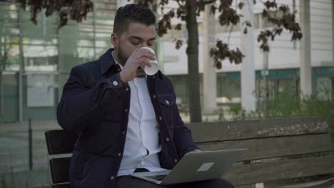 Mann-Trinkt-Kaffee-Zum-Mitnehmen-Und-Benutzt-Laptop-Im-Freien